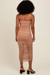 woman wearing a nude strapless ruched midi dress with a fitted silhouette and back ruching details