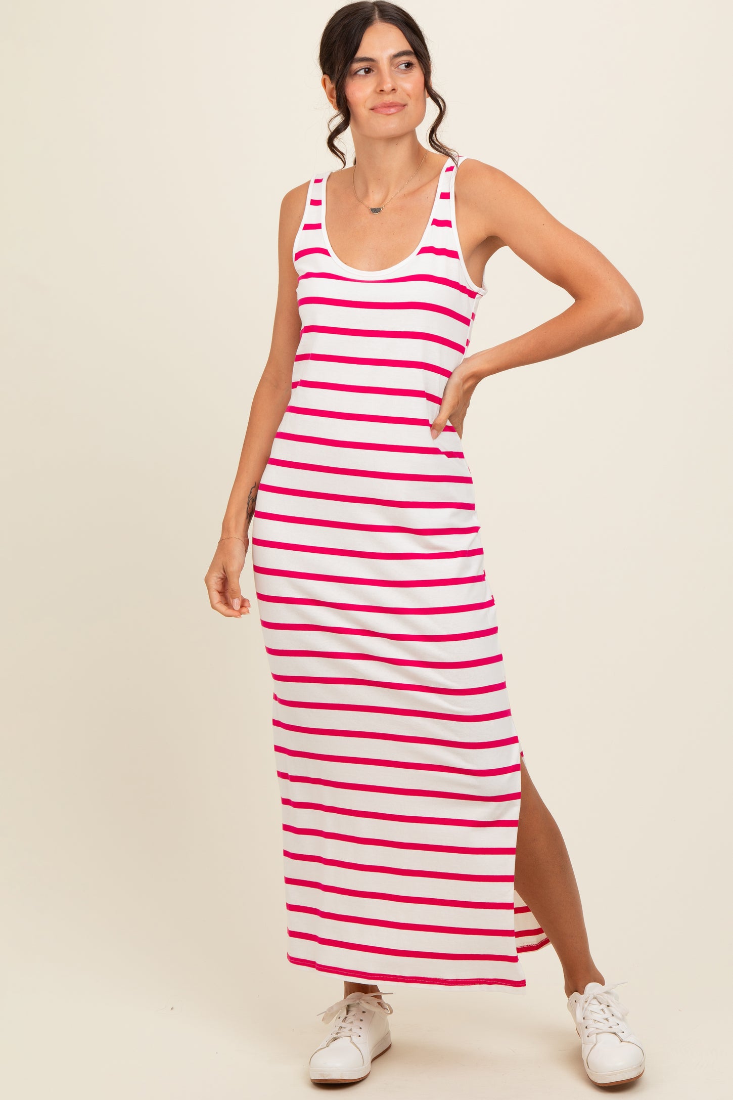 woman wearing a white and pink striped maxi dress with a side slit and casual sneakers