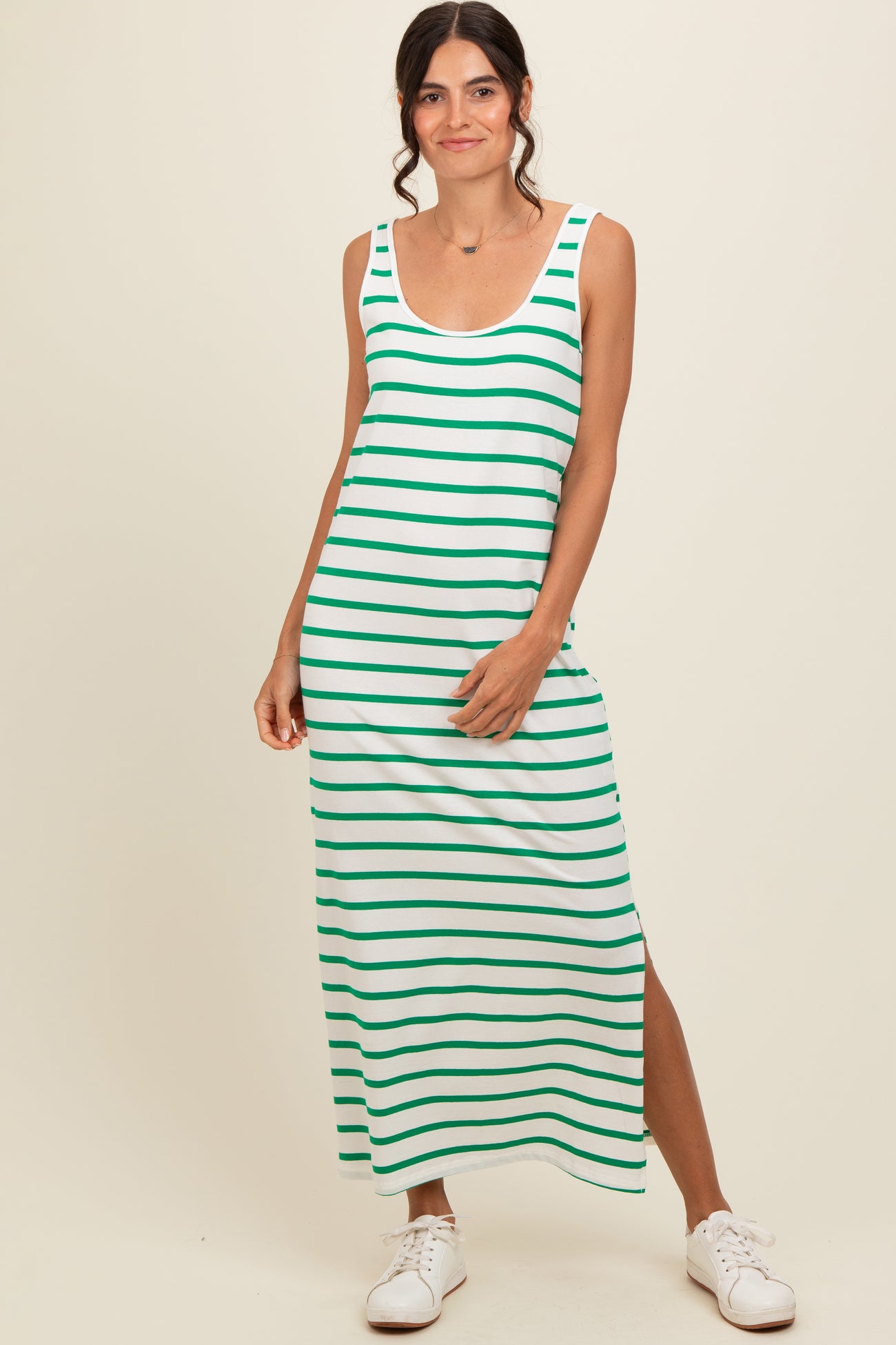 woman wearing a green and white striped maxi dress with a side slit and casual white sneakers