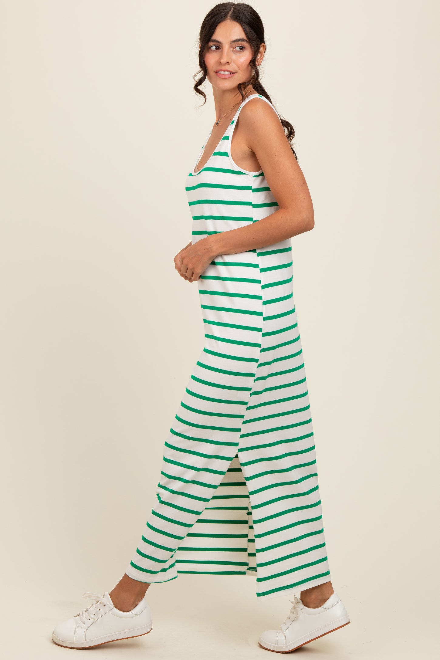 woman wearing a green and white striped maxi dress with a side slit and white sneakers