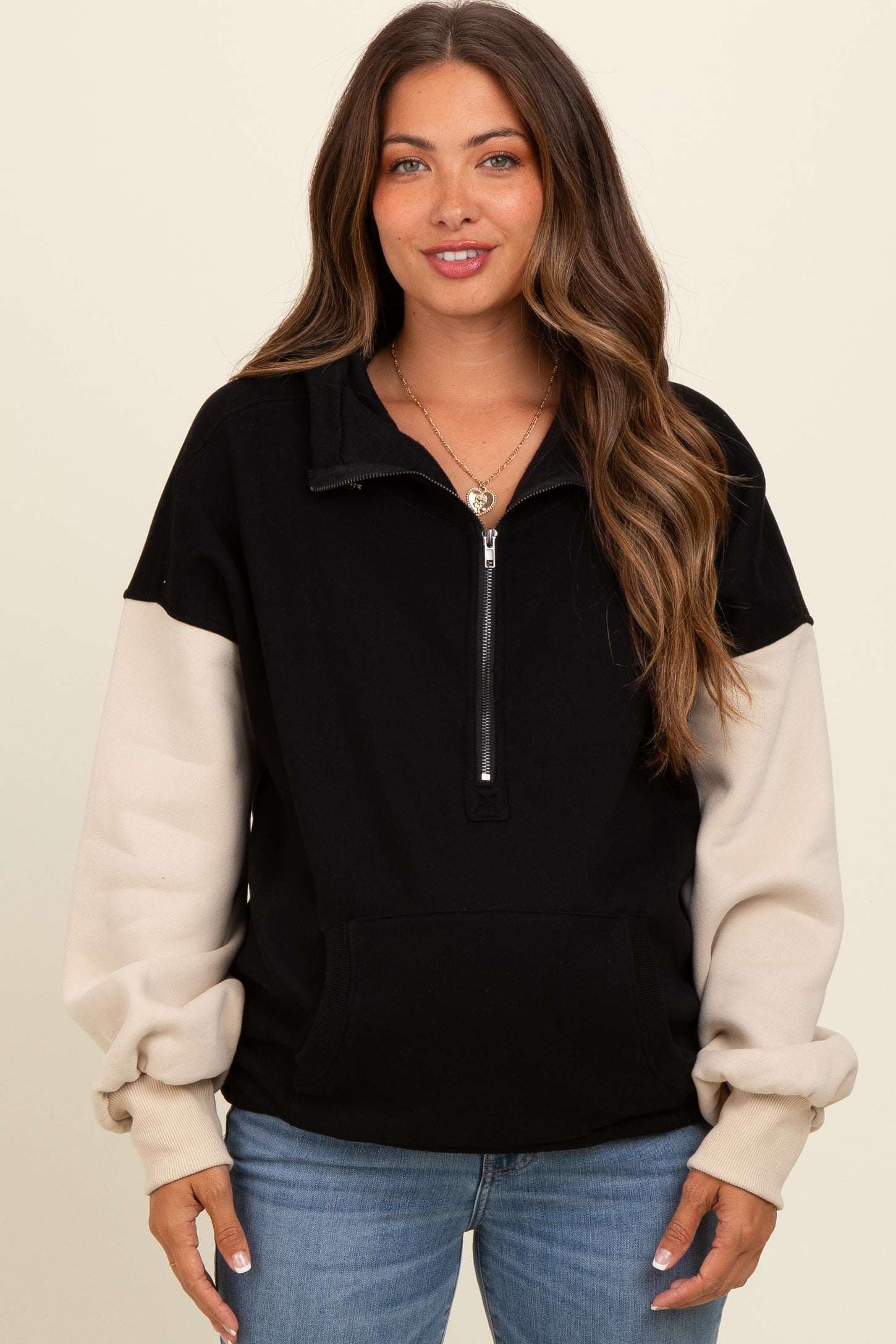 woman wearing a black and beige color block maternity pullover sweatshirt with a half zipper and front pocket