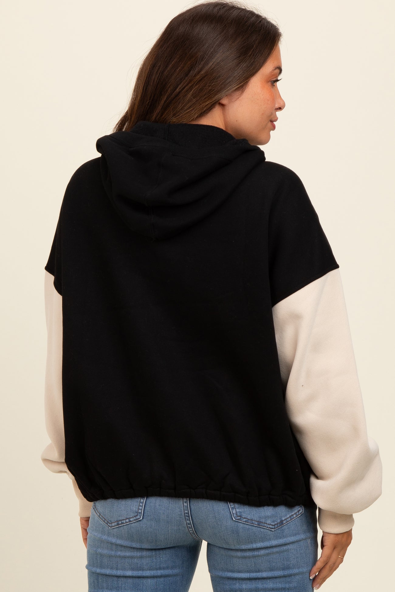 woman wearing a black and cream color block maternity hoodie with a relaxed fit and pullover style