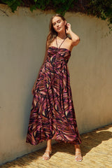 woman wearing a strapless maxi dress with a vibrant multicolor leaf pattern and a fitted bodice