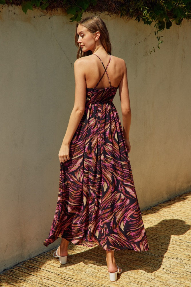woman wearing a backless maxi dress with a colorful swirl pattern and thin crisscross straps