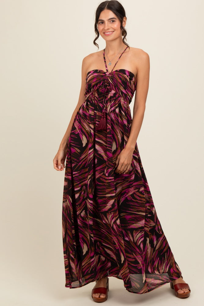 woman wearing a strapless black maxi dress with pink and orange tropical print and a tie waist detail