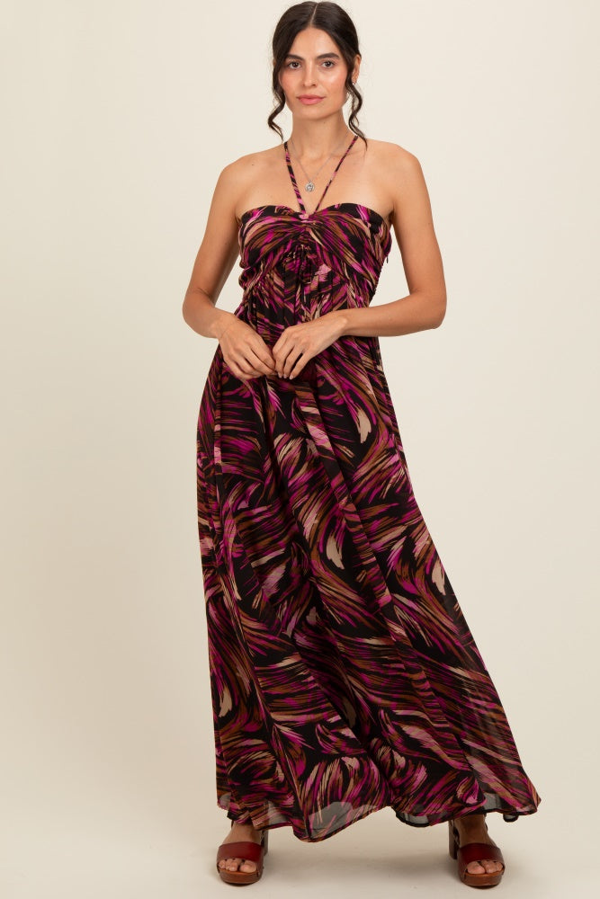 woman wearing a black maxi dress with pink and purple tropical print and a halter neck design