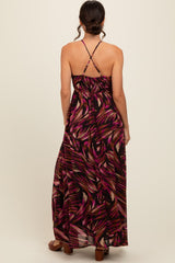 woman wearing a back view of a black maxi dress with a colorful abstract pattern and crisscross straps