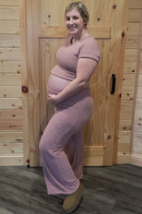 woman wearing a light pink maternity two-piece loungewear set and holding her baby bump