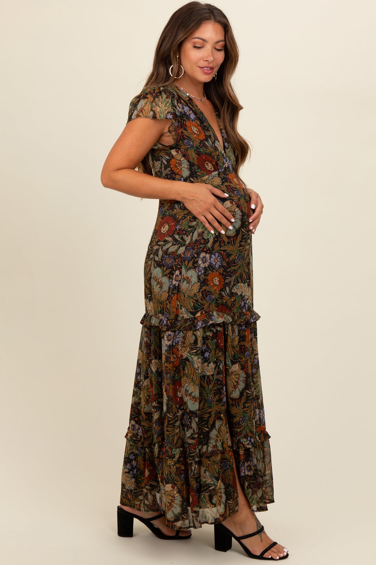 woman wearing a floral maxi maternity dress with ruffles, holding her baby bump