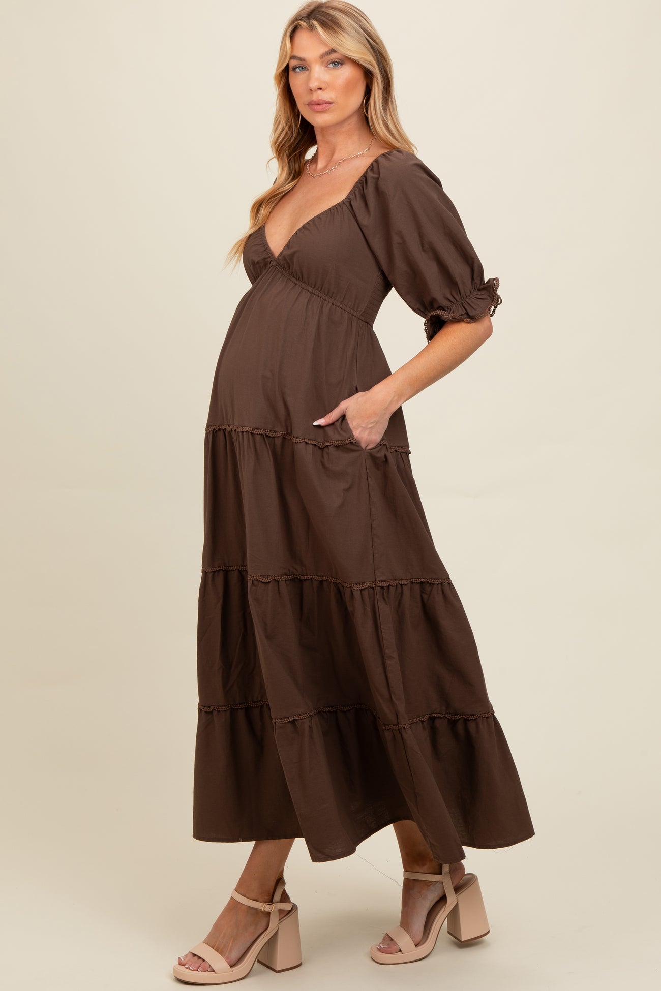woman wearing a brown tiered maternity dress with short puff sleeves and a baby bump visible