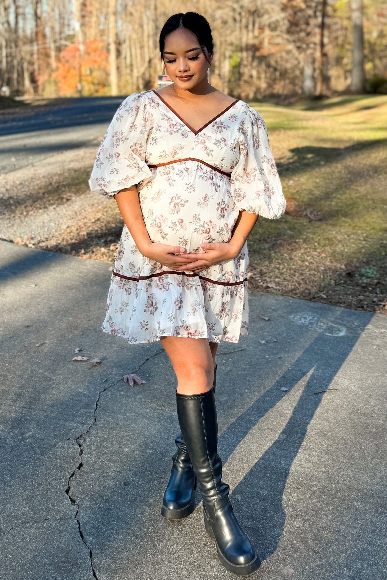 woman wearing a floral print maternity dress with puff sleeves and holding her baby bump