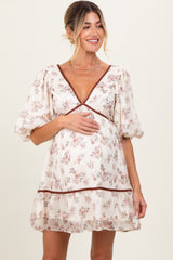 woman wearing a cream floral maternity dress with puff sleeves and a baby bump visible