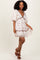 woman wearing a floral white mini dress with puff sleeves and a deep v-neck, posing with one hand on her hip