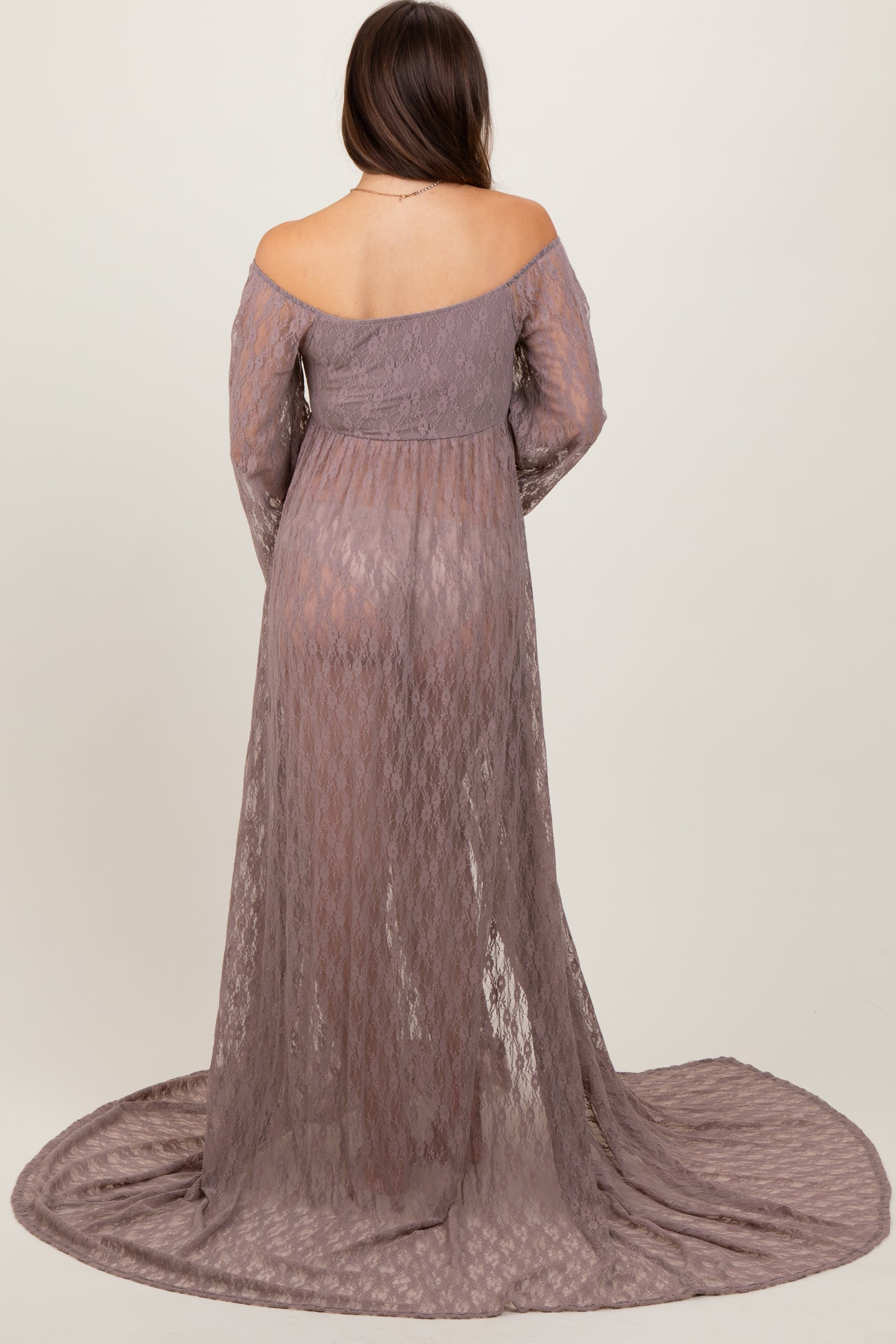woman wearing a lavender lace off-shoulder maternity gown with long sleeves and a flowing train, showing her baby bump