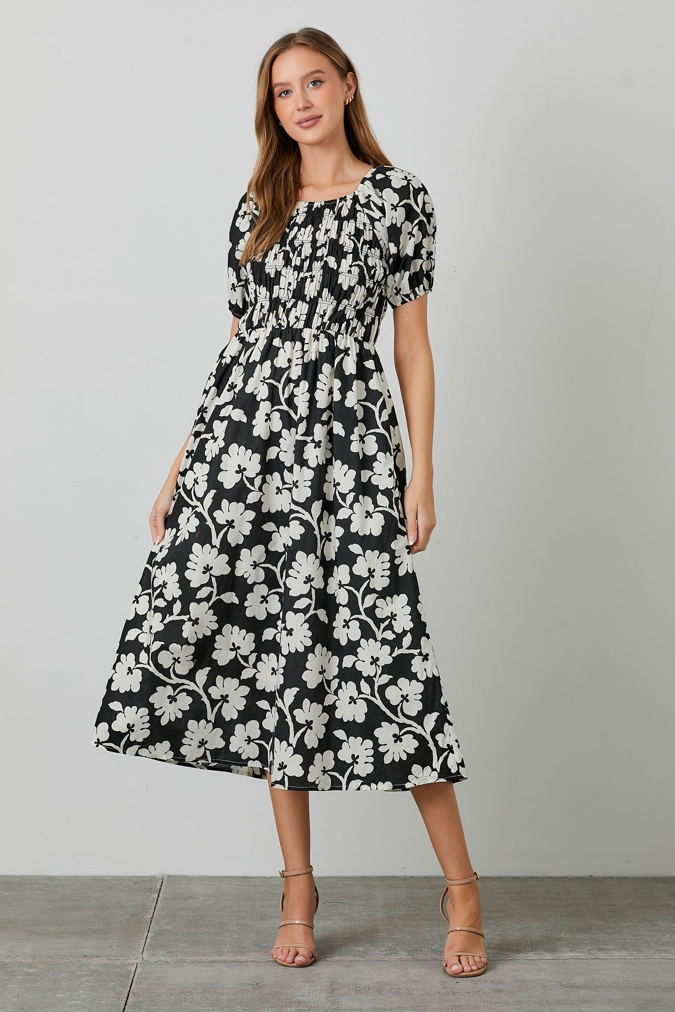 woman wearing a black and white floral midi dress with puff sleeves and a smocked bodice