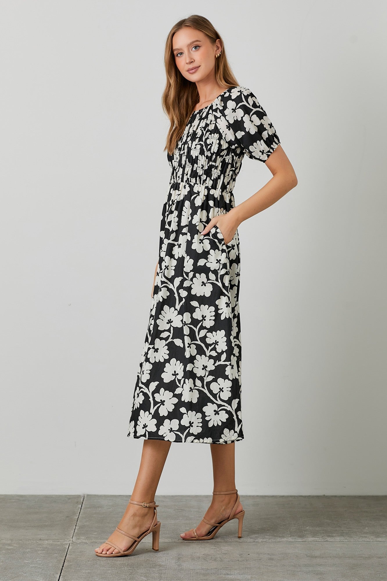 woman wearing a black and white floral midi dress with short sleeves and pockets