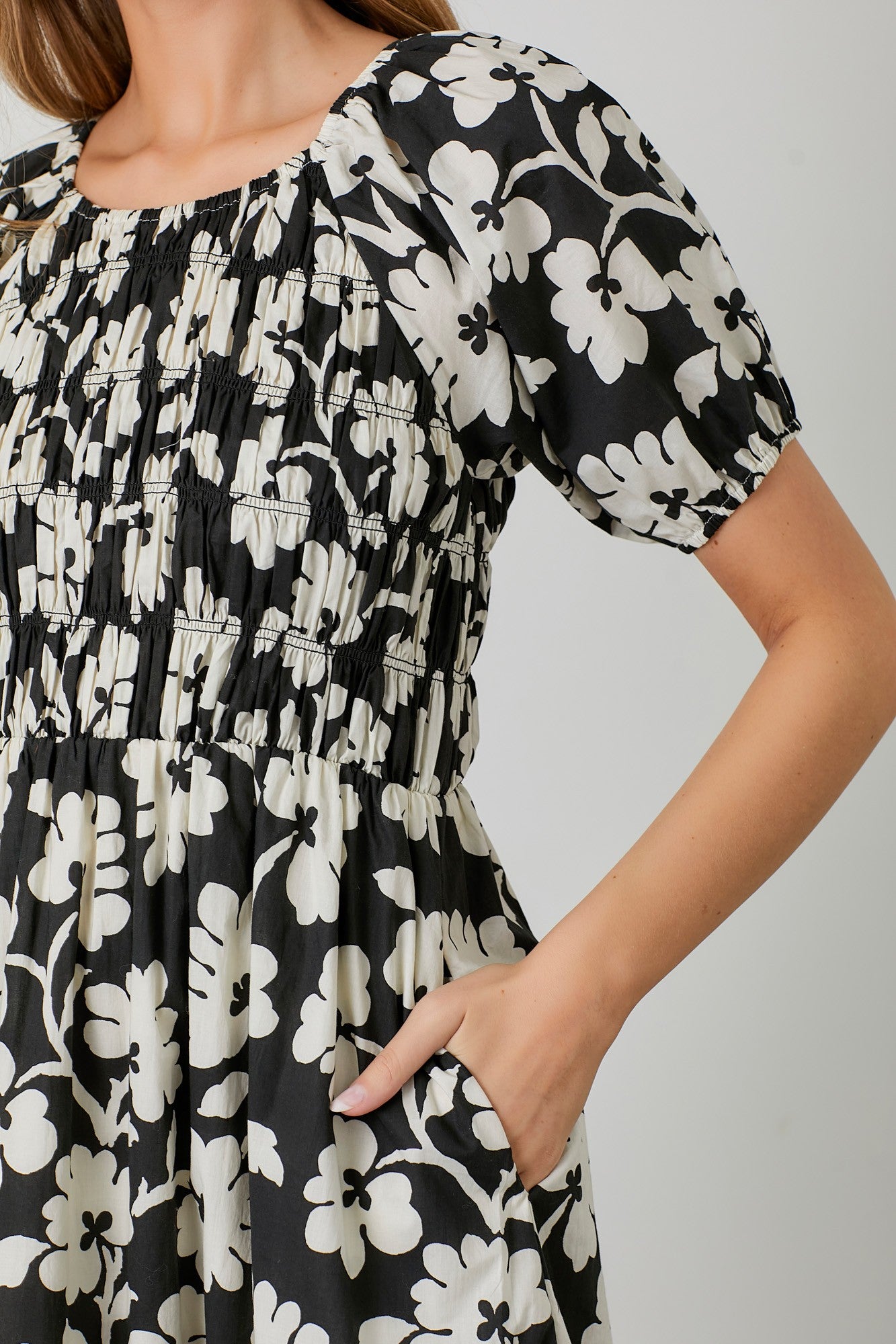 woman wearing a black and white floral printed dress with puff sleeves and pockets