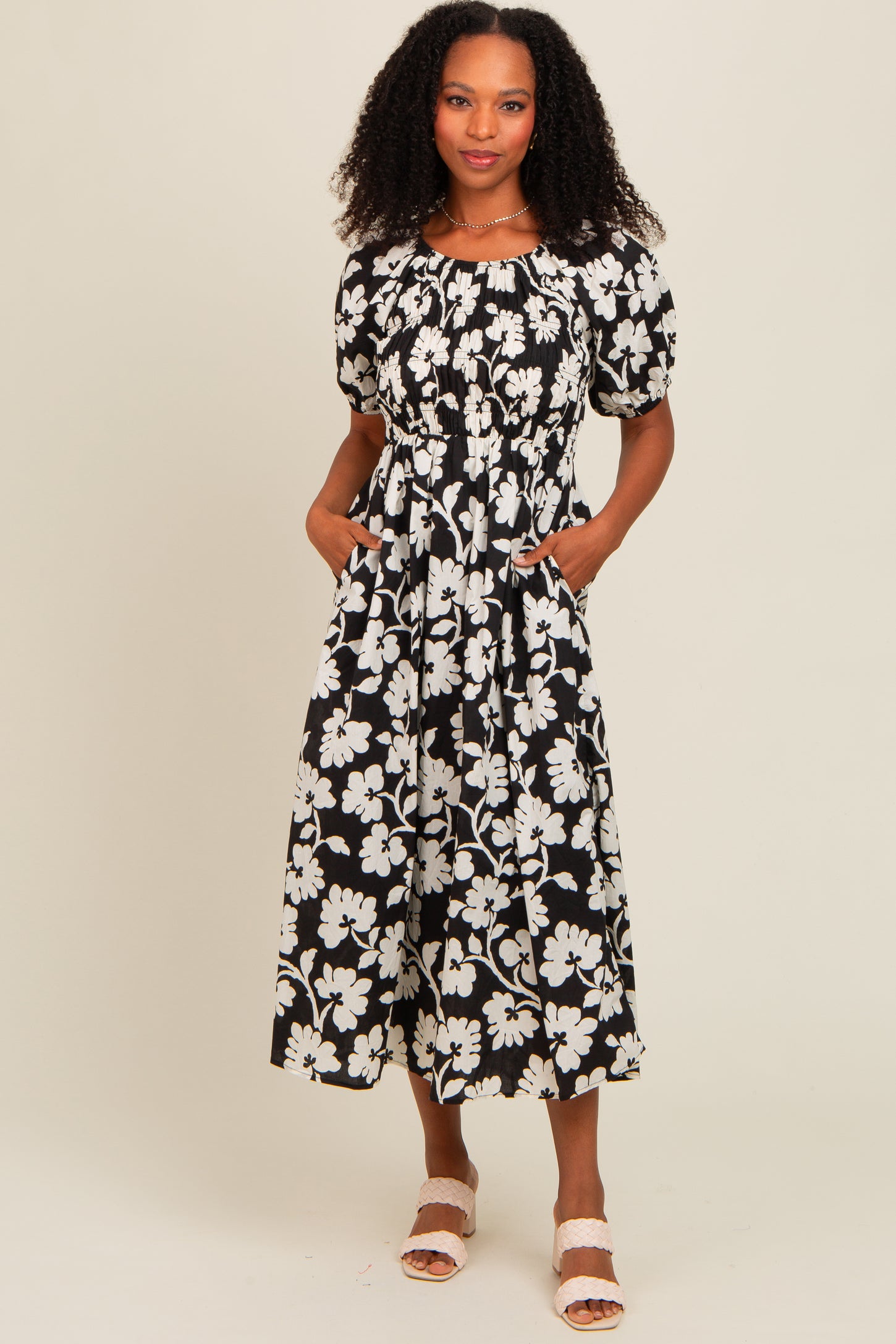 woman wearing a black and white floral maxi dress with puff sleeves and side pockets