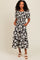 woman wearing a black and white floral maxi dress with puff sleeves and side pockets