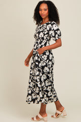 woman wearing a black floral maxi dress with short puff sleeves and pockets, standing in profile