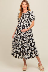woman wearing a black and white floral maternity dress with a smocked bodice and a baby bump visible