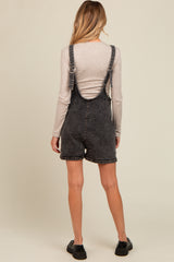 woman wearing a gray denim maternity romper with adjustable straps and a relaxed fit, showing a maternity silhouette