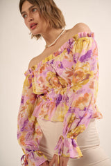 woman wearing a purple floral off-the-shoulder peplum top with ruffled sleeves and a cinched waist