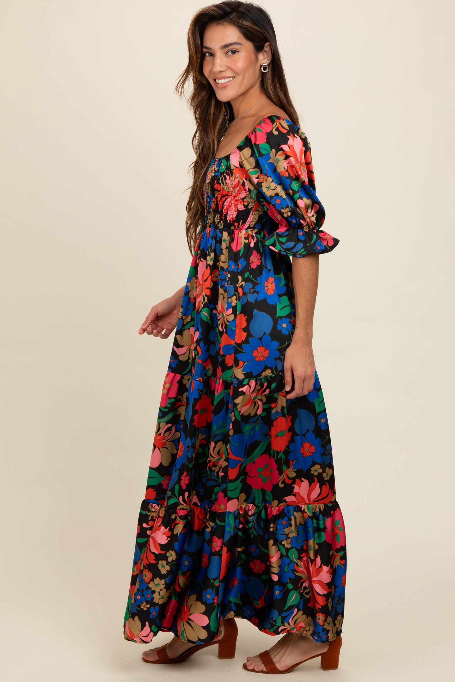 woman wearing a vibrant floral maxi dress with puff sleeves and a tiered skirt, smiling in profile