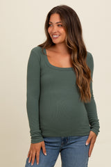 woman wearing a green long sleeve maternity top with a square neckline and a baby bump visible