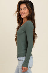 woman wearing a dark green ribbed long sleeve top with a fitted style and smiling at the camera