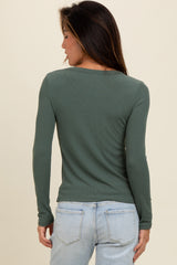 woman wearing a dark green long sleeve ribbed top, shown from the back with light blue jeans
