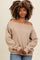 woman wearing a beige off-the-shoulder sweatshirt with long sleeves and relaxed fit, posing with hands clasped in front