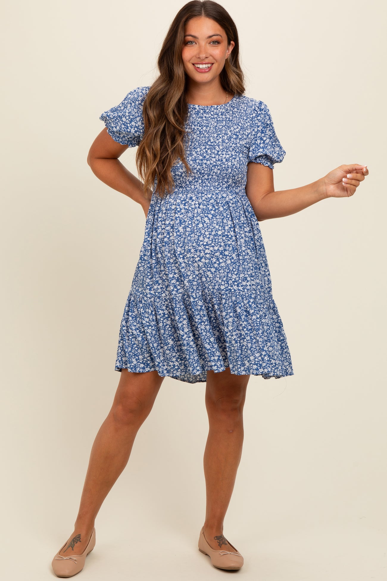 woman wearing a blue floral short sleeve maternity dress and showing her baby bump
