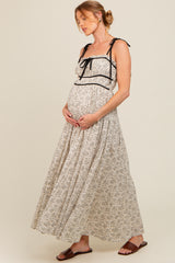 woman wearing a floral maternity maxi dress with adjustable straps, holding her baby bump