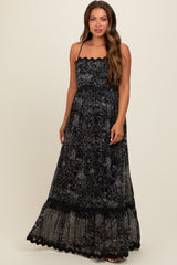 woman wearing a black floral lace maternity maxi dress with adjustable straps and a tiered skirt