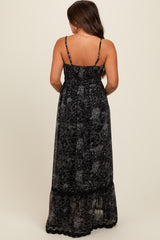 woman wearing a black maternity maxi dress with floral print and adjustable straps, showing the back view