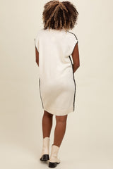 woman wearing a cream sleeveless knit sweater dress with black trims and ankle boots, shown from the back