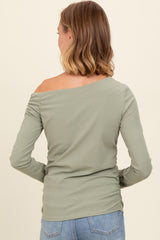 woman wearing a light green off-the-shoulder long sleeve top with ruched detailing on the side