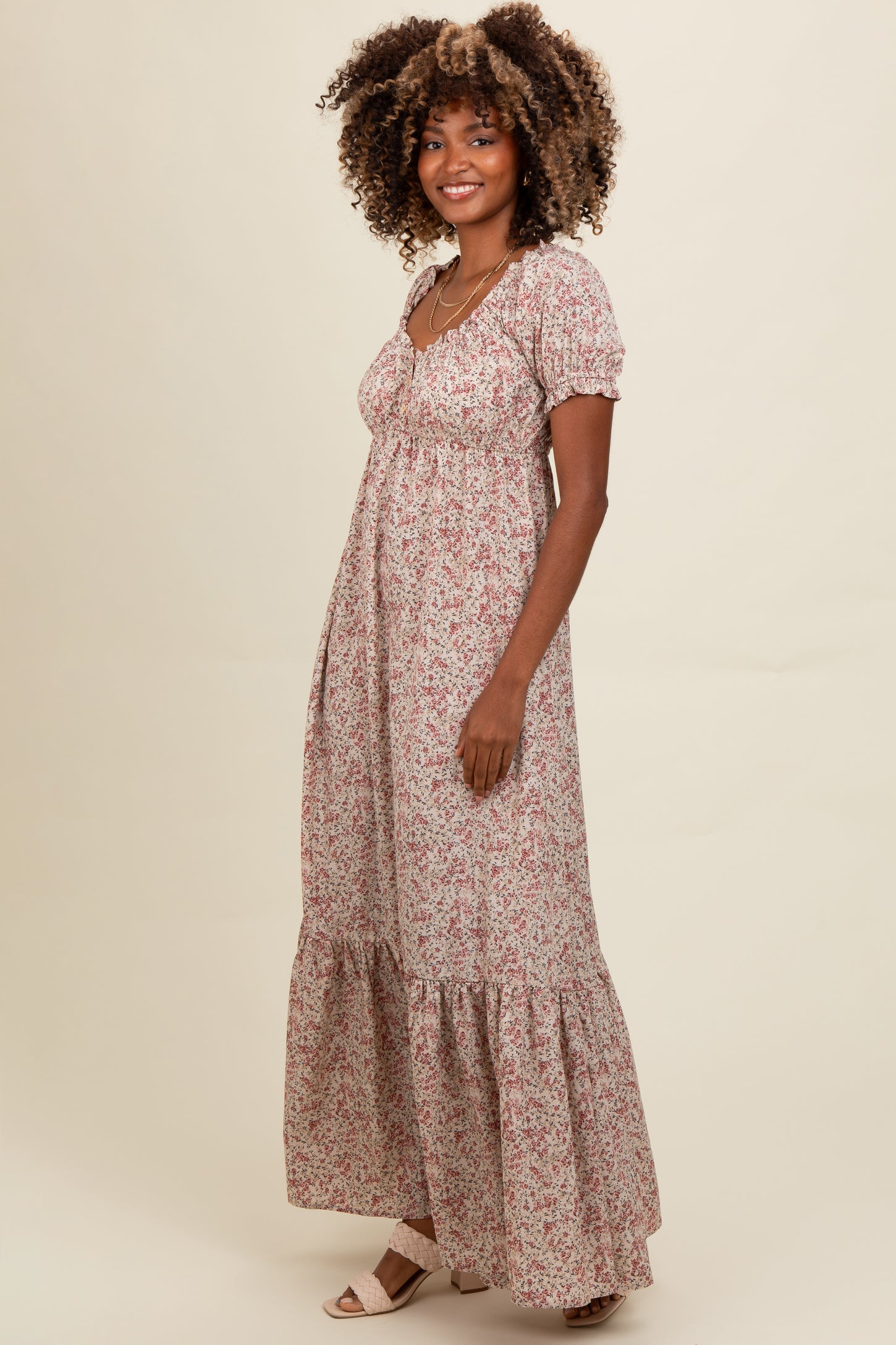 woman wearing a floral maxi dress with puff sleeves and a tiered hem, standing against a neutral background