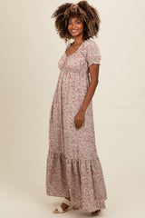 woman wearing a floral maxi dress with puff sleeves and a tiered hem, standing against a neutral background