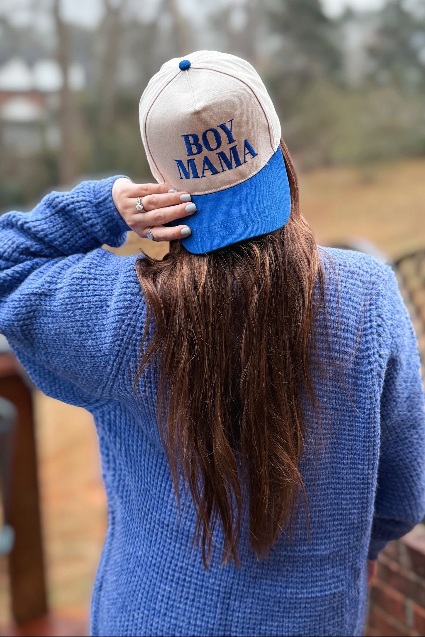 woman wearing a blue knitted sweater and a beige and blue cap that says "boy mama