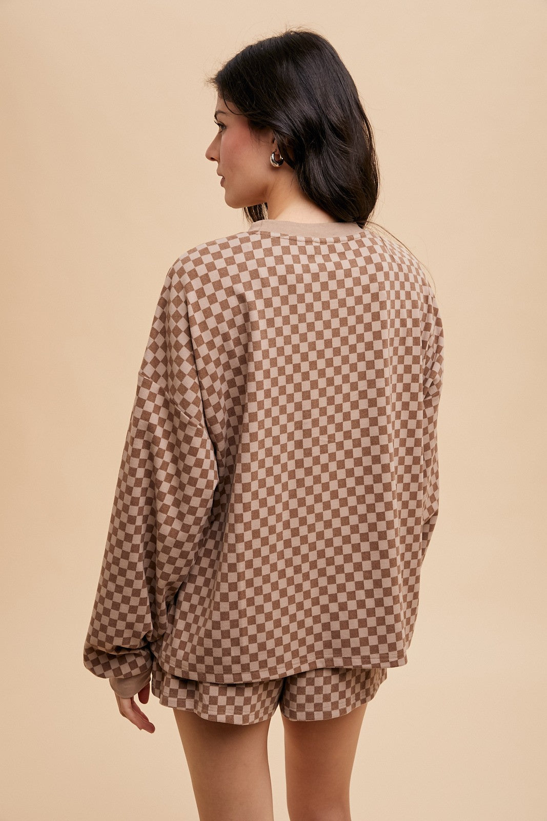 woman wearing a brown checkered oversized sweater and matching shorts, viewed from the back