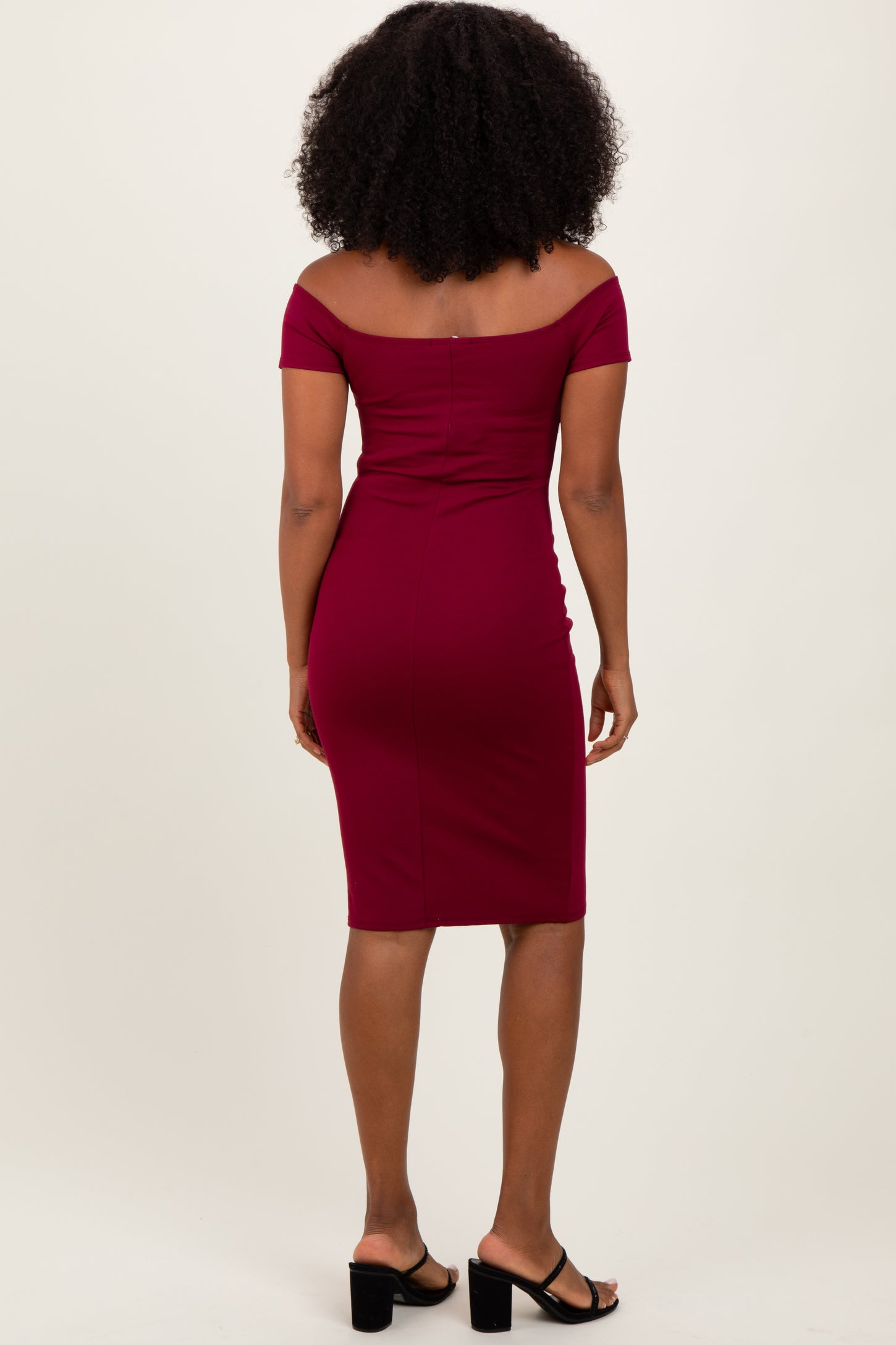 woman wearing a burgundy off-the-shoulder fitted midi dress with a bodycon silhouette and a sleek design