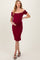 woman wearing a burgundy off-shoulder maternity dress and holding her baby bump