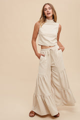 woman wearing a cream sleeveless crop top and wide-leg tiered pants with pockets