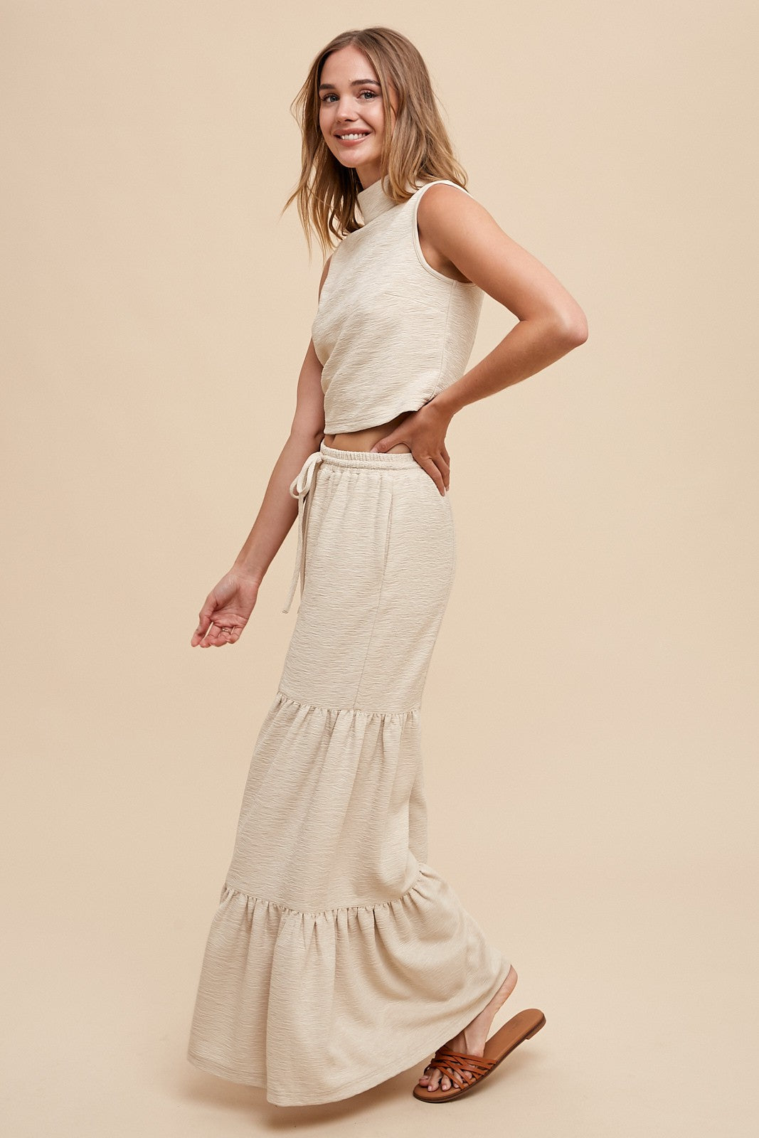 woman wearing a beige cropped tank top and a matching tiered maxi skirt with drawstring waist and sandals