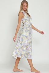 woman wearing a lavender floral midi dress with a wrap design and tie detail at the waist, standing barefoot