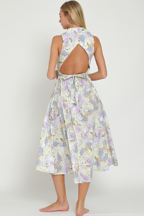 woman wearing a floral print midi dress with a back cutout and tie detail, showing an open back design