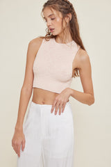 woman wearing a light pink ribbed cropped tank top and white high-waisted pants