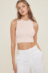 woman wearing a light pink ribbed crop top with a high neckline and paired with white wide-leg pants